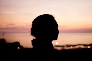 A woman in profile, silhouetted against a sunset sky