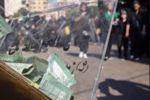 Riot police behind shields facing a crowd carrying green banners