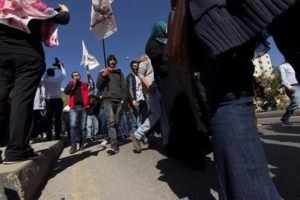 Protesters carrying flags, seen past a figure in the foreground