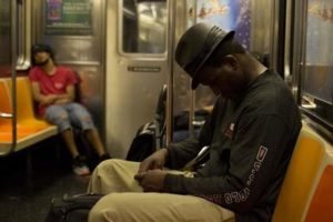 A man writing in a notebook on a subway train