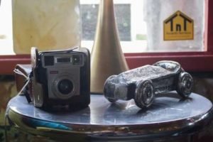 A vintage camera and a toy car arranged on a metal table