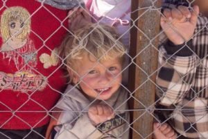 A child smiling through a wire mesh fence