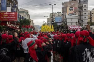 A procession of mourners in red headwear and black robes