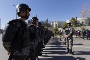 A line of riot police in helmets and body armour drawn across a road